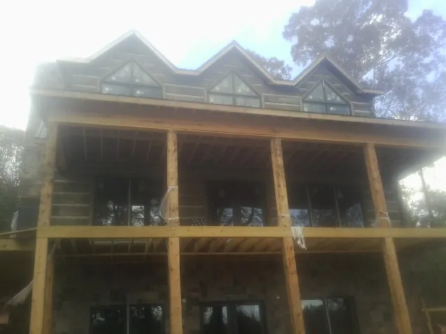 Dormers and porch framing on a large log home under construction — Roof Coating work by our crew in Moscow